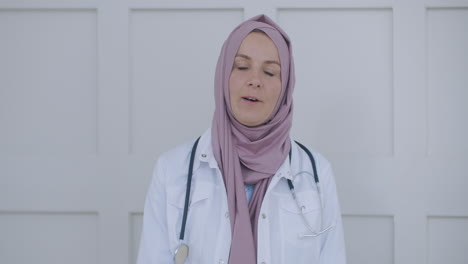 Mujer-árabe-Musulmana-Con-Hijab-Médico-A-Través-De-Videoconferencia.-Retrato-De-Una-Doctora-Musulmana.-Una-Profesional-De-La-Salud-Vestida-Con-Bata-Y-Un-Hiyab-Sentada-En-Las-Escaleras-De-Un-Hospital.